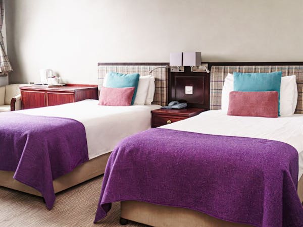 Twin beds with matching tweed blankets and cushions, check tweed headboards and neutral walls.