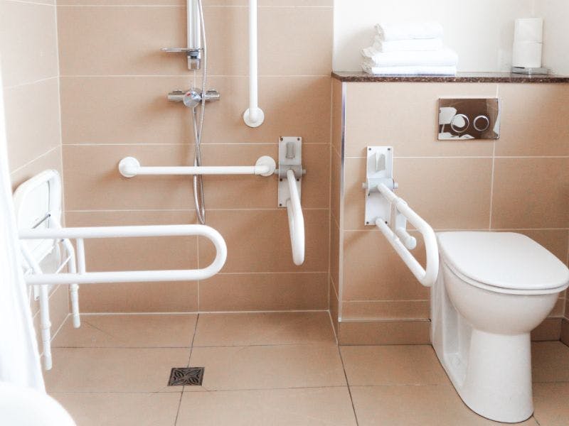 A modern accessible bathroom with walk in shower with grab rails.