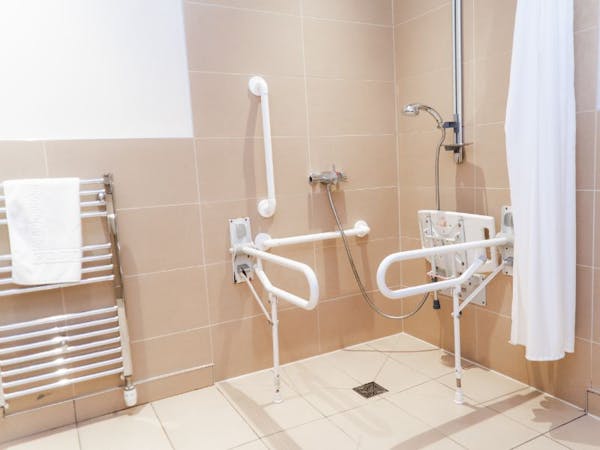 A modern accessible bathroom with walk in shower with grab rails.