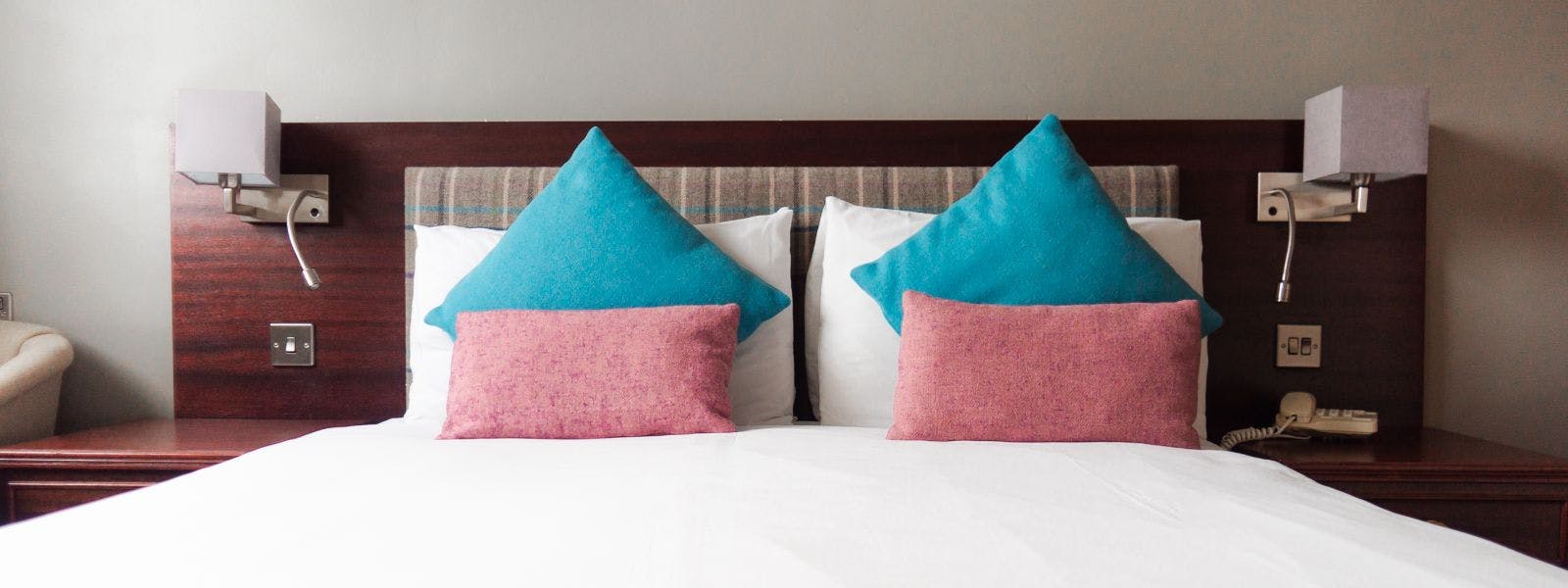 A bed with two blue pillows and a white sheet, creating a cosy atmosphere.
