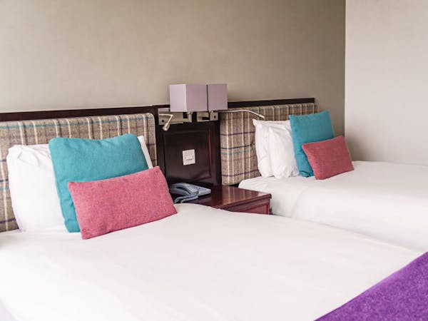 Twin beds with matching tweed blankets and cushions, check tweed headboards and neutral walls.