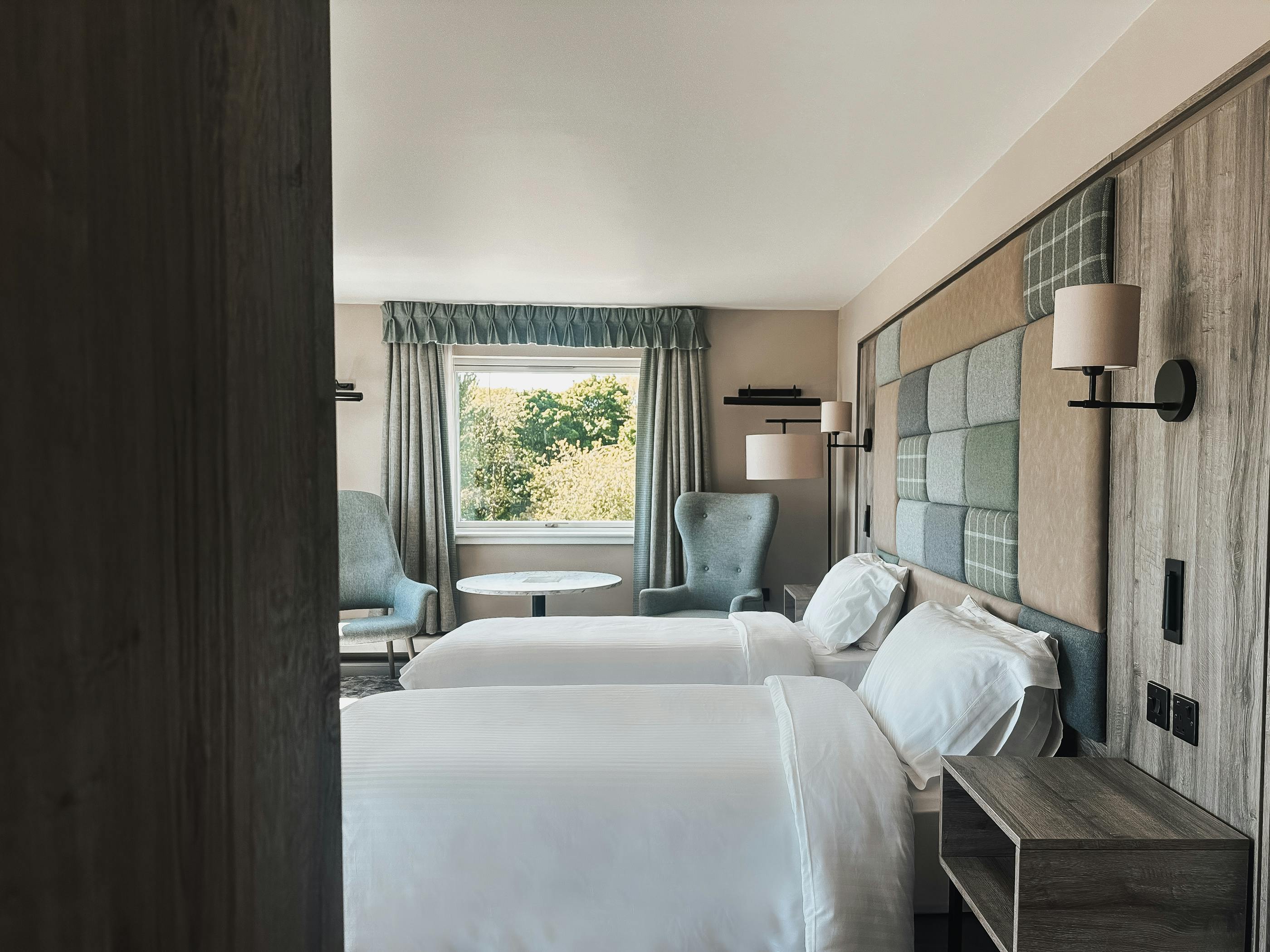 Executive twin room at Cabarfeidh Hotel featuring two beds and a large window with natural light.