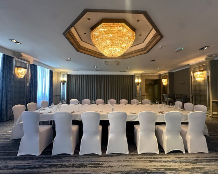 An expansive room with white chairs and a beautiful chandelier hanging from the ceiling.