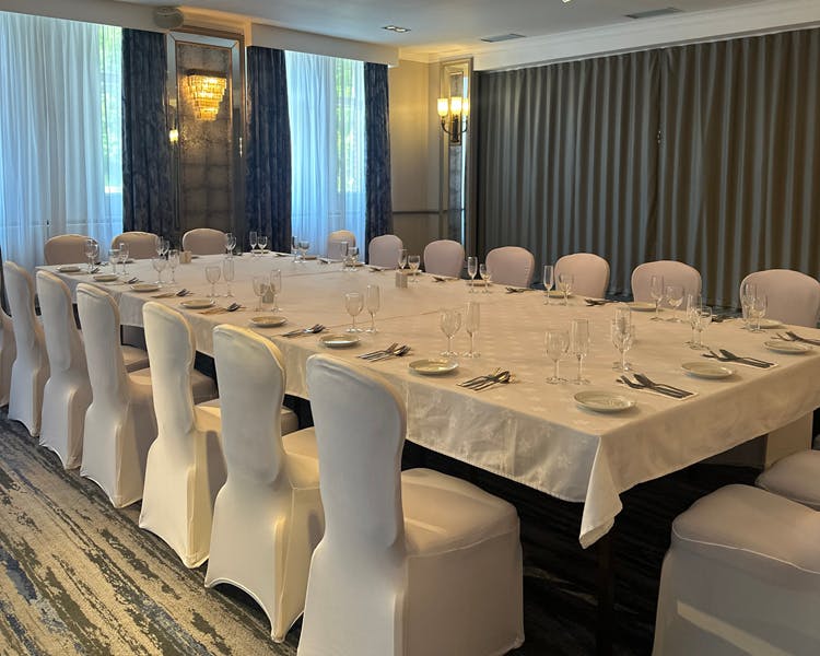 Elegant oak suite at the Cabarfeidh featuring a large table and white chairs, perfect for events or gatherings.