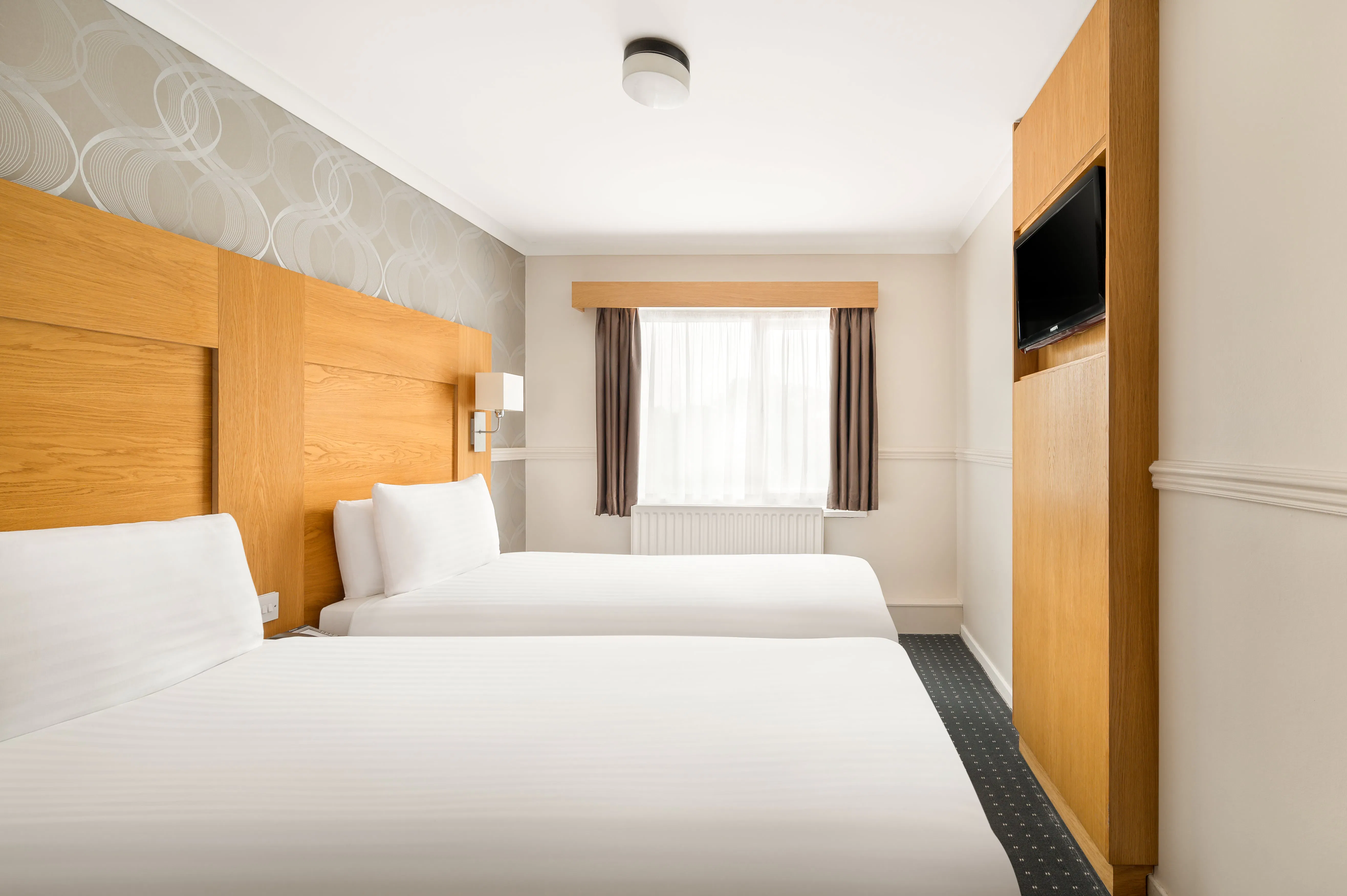 Rooms Inn Newcastle twin room side view of two single beds next to a window