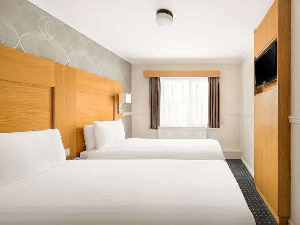 Rooms Inn Newcastle twin room side view of two single beds next to a window