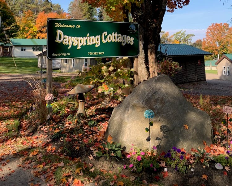 Entrance to Dayspring Cottages sign framed by vibrant fall foliage.