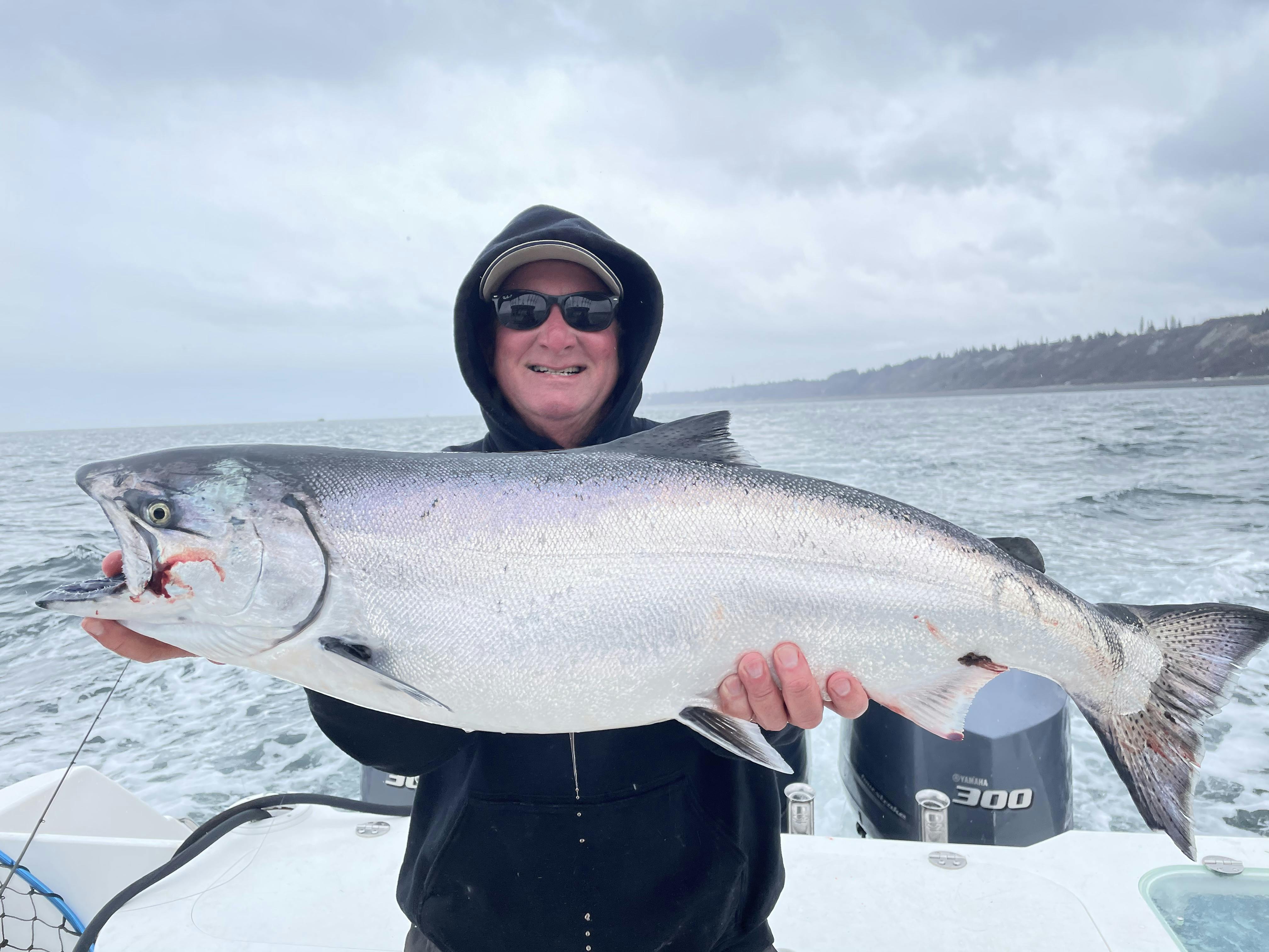 Fisherman posing with a king salmon he caught while on a saltwater fishing trip with Deep Creek Fishing Club, Alaska