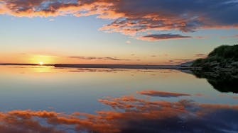 Orange dawn reflected in still water.
