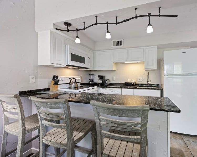 Full kitchen in Sea Crest Surf & Racquet Club villa featuring granite countertops, white cabinetry, modern appliances, and a