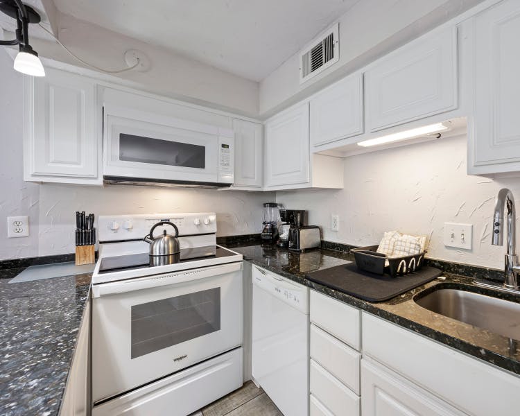 Modern white cabinetry kitchen with bar seating at Sea Crest Surf & Racquet Club condo