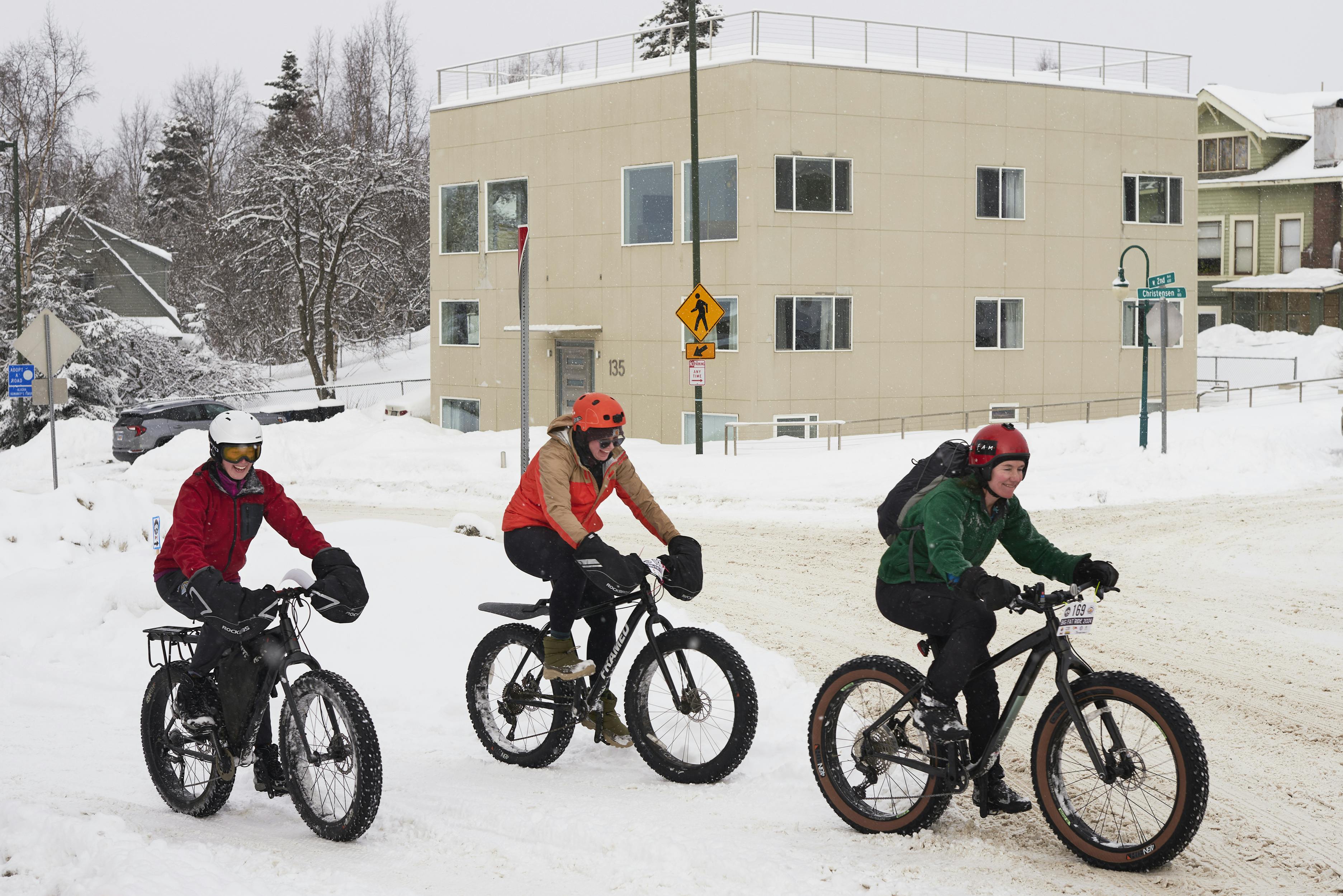 Cyclists riding fat tire bikes ride past Snob Hollow Inn during the Fur Rondy festival in Anchorage.