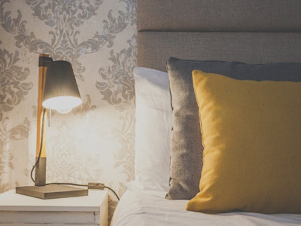 Pillows are on the bed of a beautifully decorated double room with ensuite, a table lamp creates a cozy atmosphere