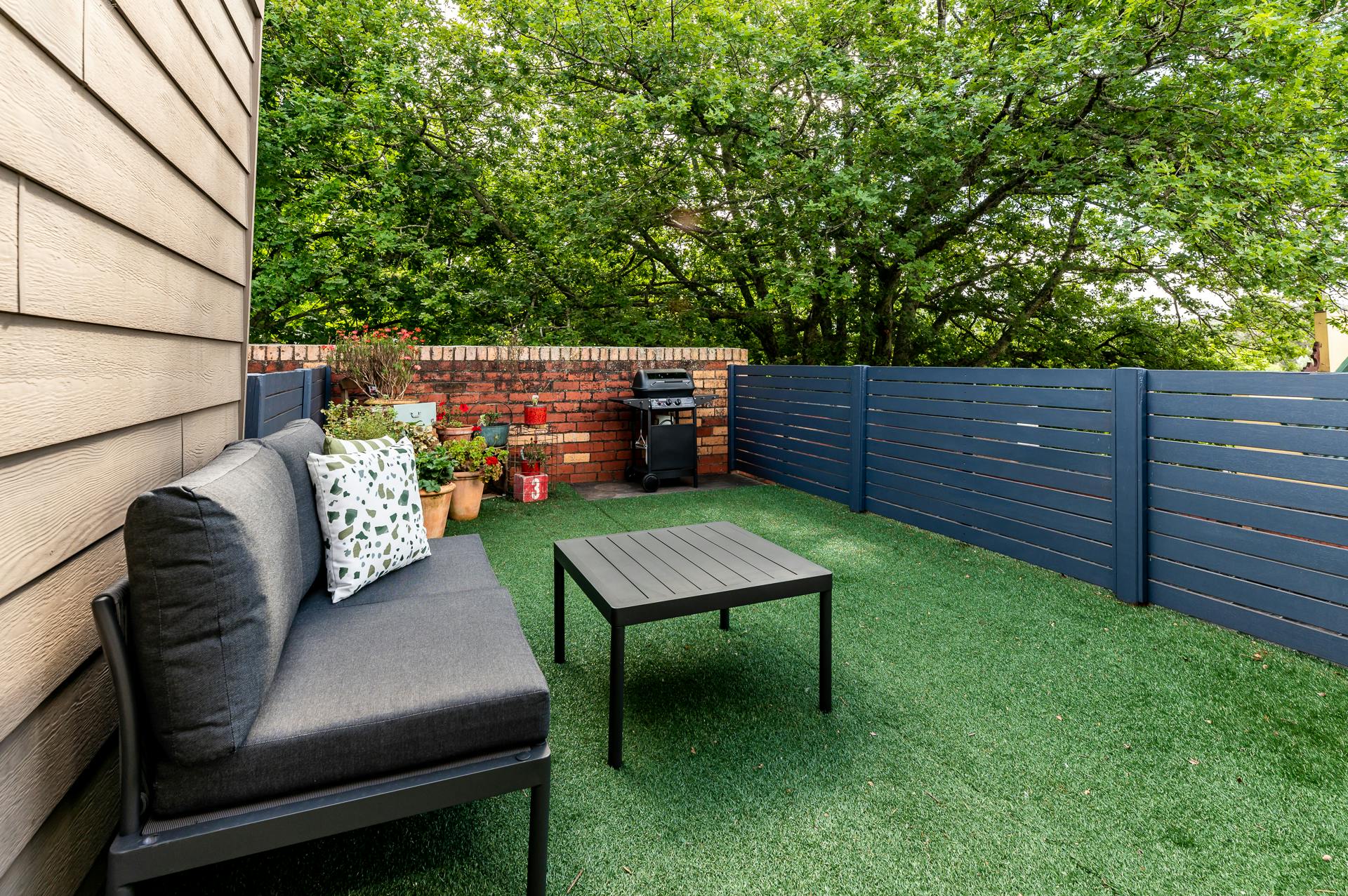 Large outside deck with table and chairs, bbq and flowers