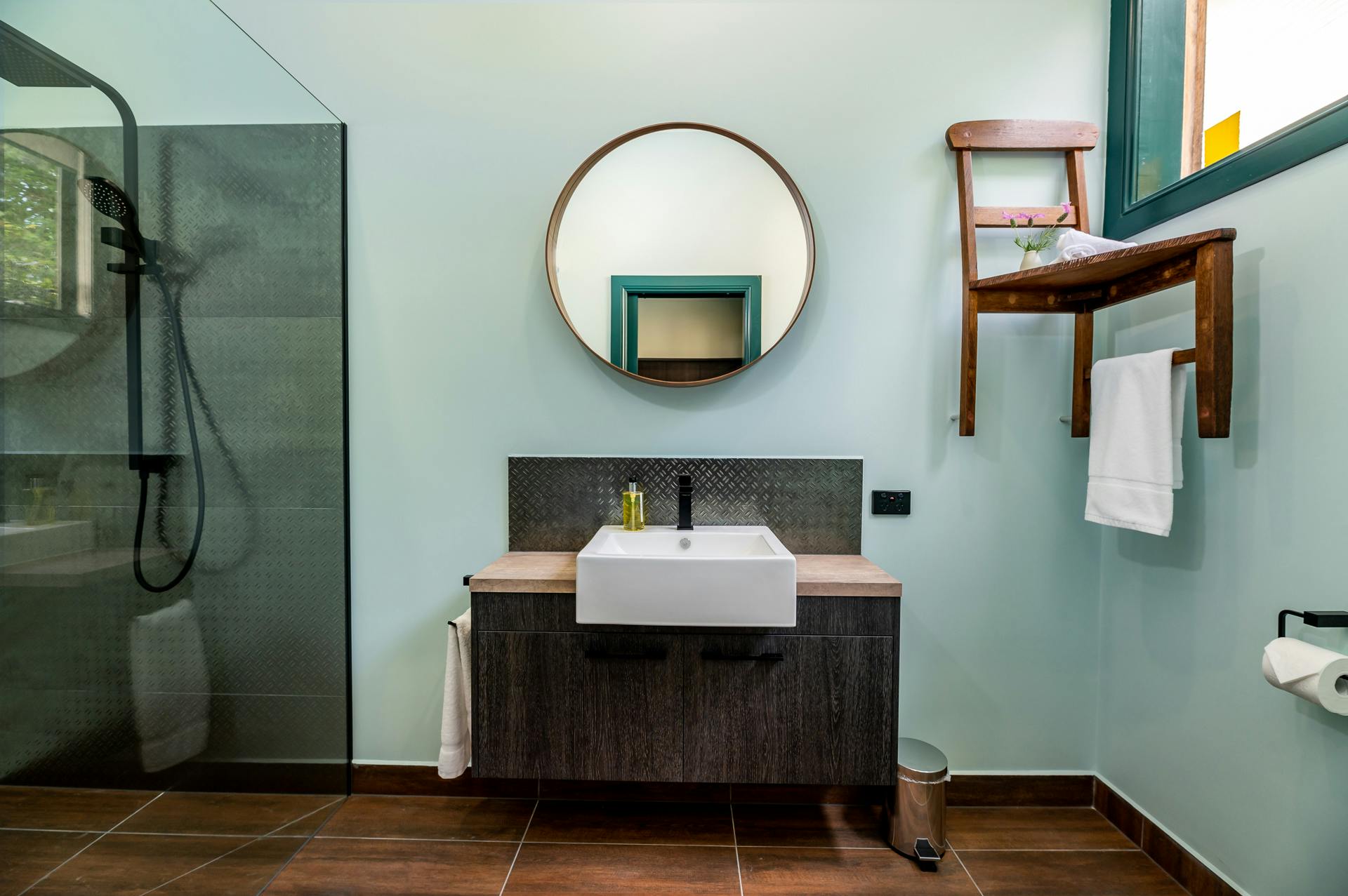 Funky bathroom with large mirror and chair on wall