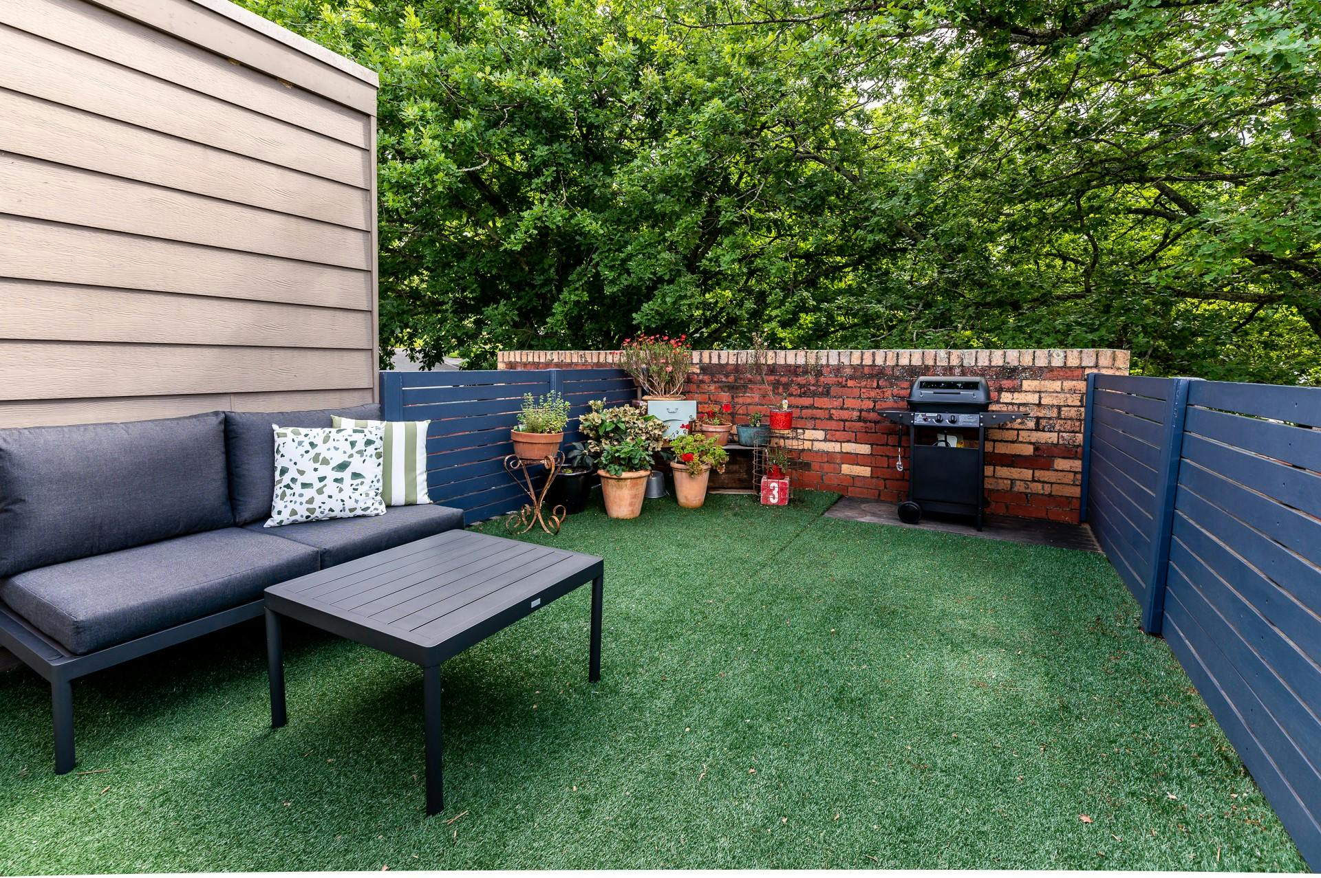 Large deck in tree tops with table and chairs, flowers and bbq