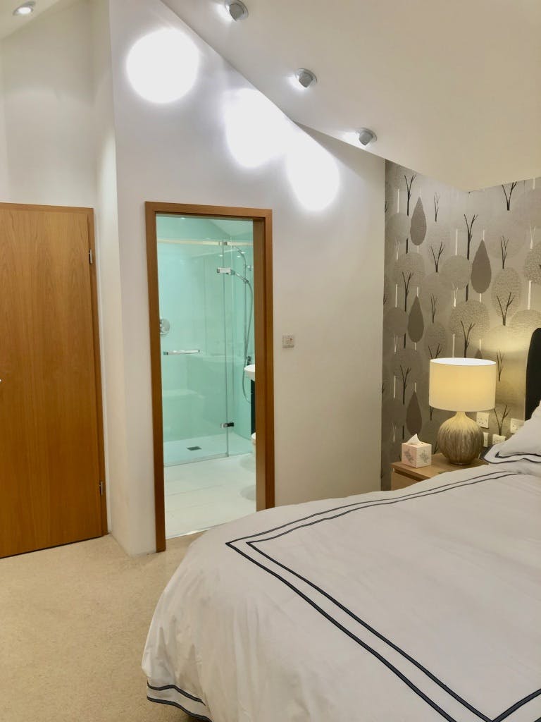 Bedroom 2 view of bedside table lamp and open ensuite door.