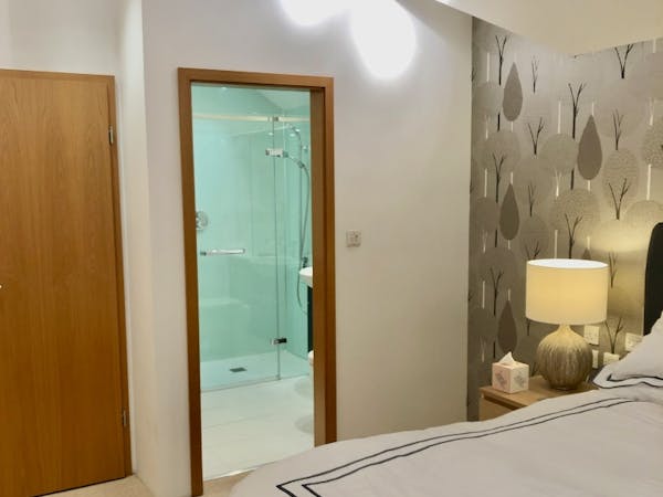 Bedroom 2 view of bedside table lamp and open ensuite door.