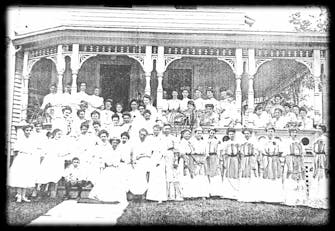 1890's photo of The Victorian on Main with several women wearing Victorian dresses standing in front of the house