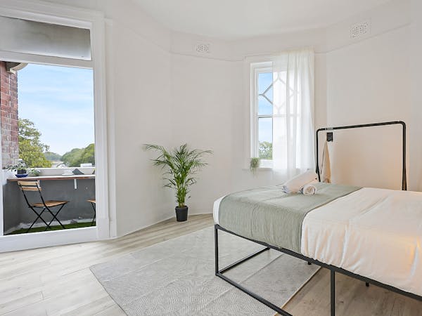 Large queen bed in deluxe double room with balcony, clothes rail, complimentary toiletries and towels.