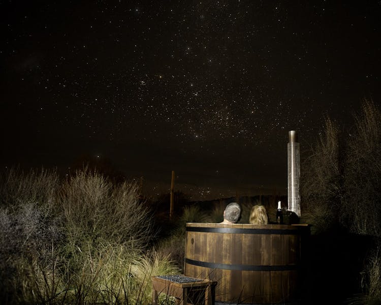 A couple in a hot tub stargazing at night at Musterer's Accommodation, Fairlie.