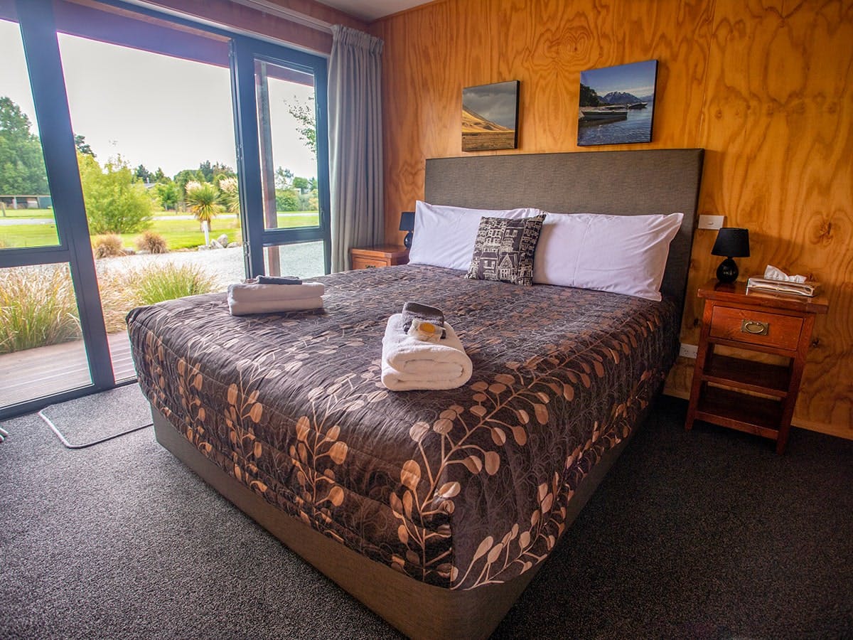 A timber bedroom with a large bed at Musterer's Accommodation, Fairlie.