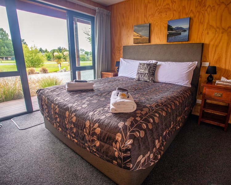 A timber bedroom with a large bed at Musterer's Accommodation, Fairlie.