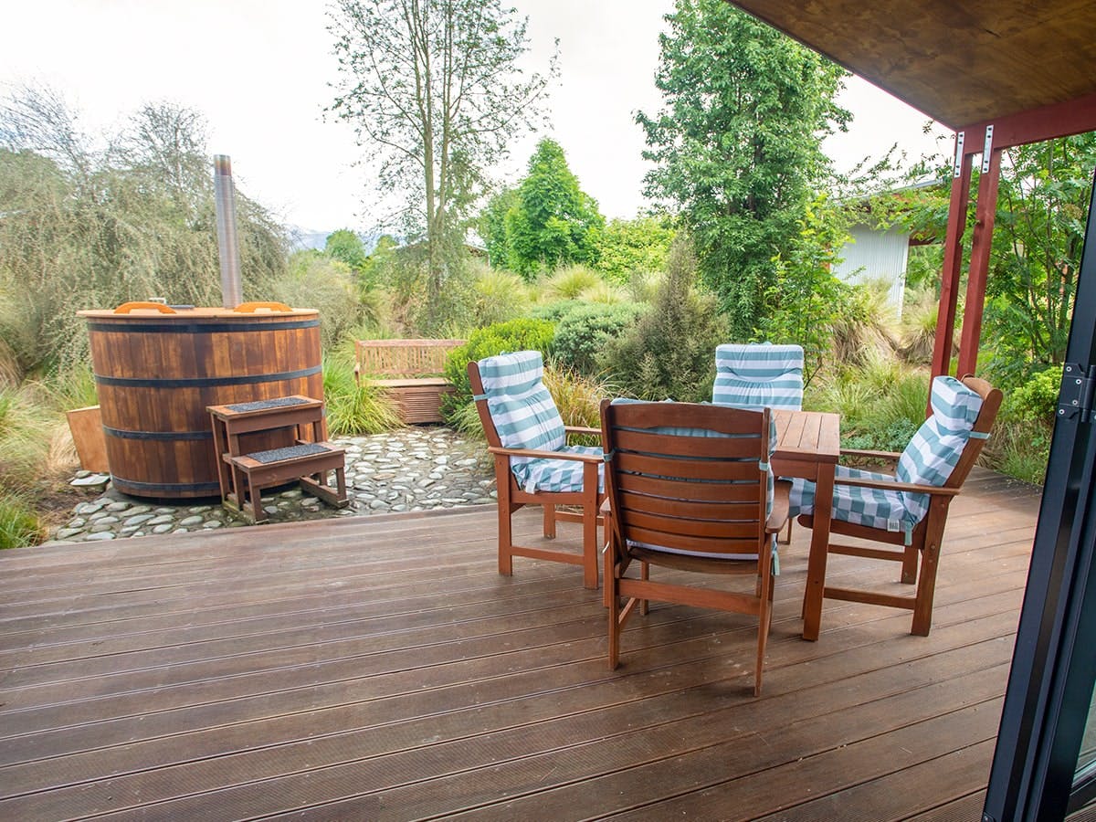 An outdoor eating area and hot tub with native plants at Musterer's Accommodation, Fairlie.