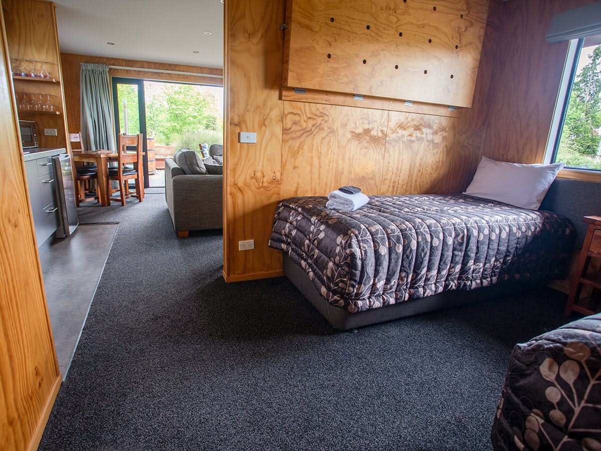 A modern-rustic living area with a bedroom nook at Musterer's Accommodation, Fairlie.