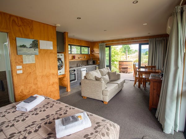 A modern-rustic living area with kitchen, couches, and large bed at Musterer's Accommodation, Fairlie.