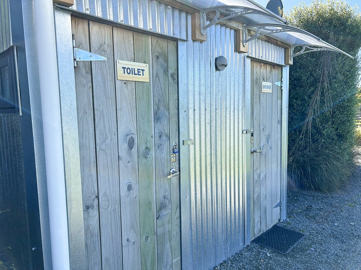 A wood and corrugated iron bathroom block with signage that says Toilet.