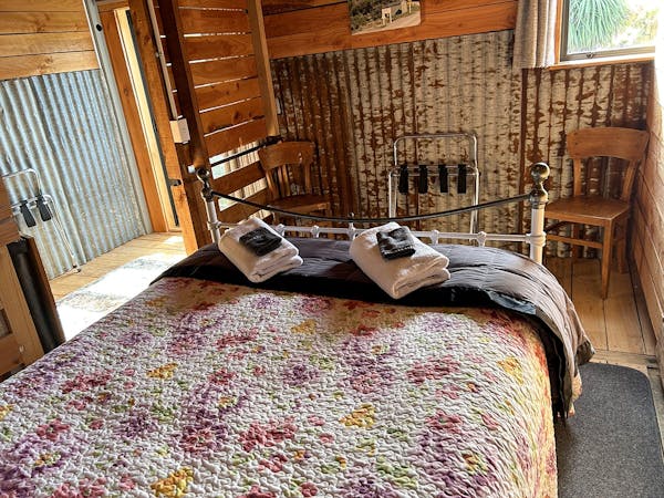 A large iron-framed bed in rustic bedroom at Musterer's Accommodation, Fairlie.