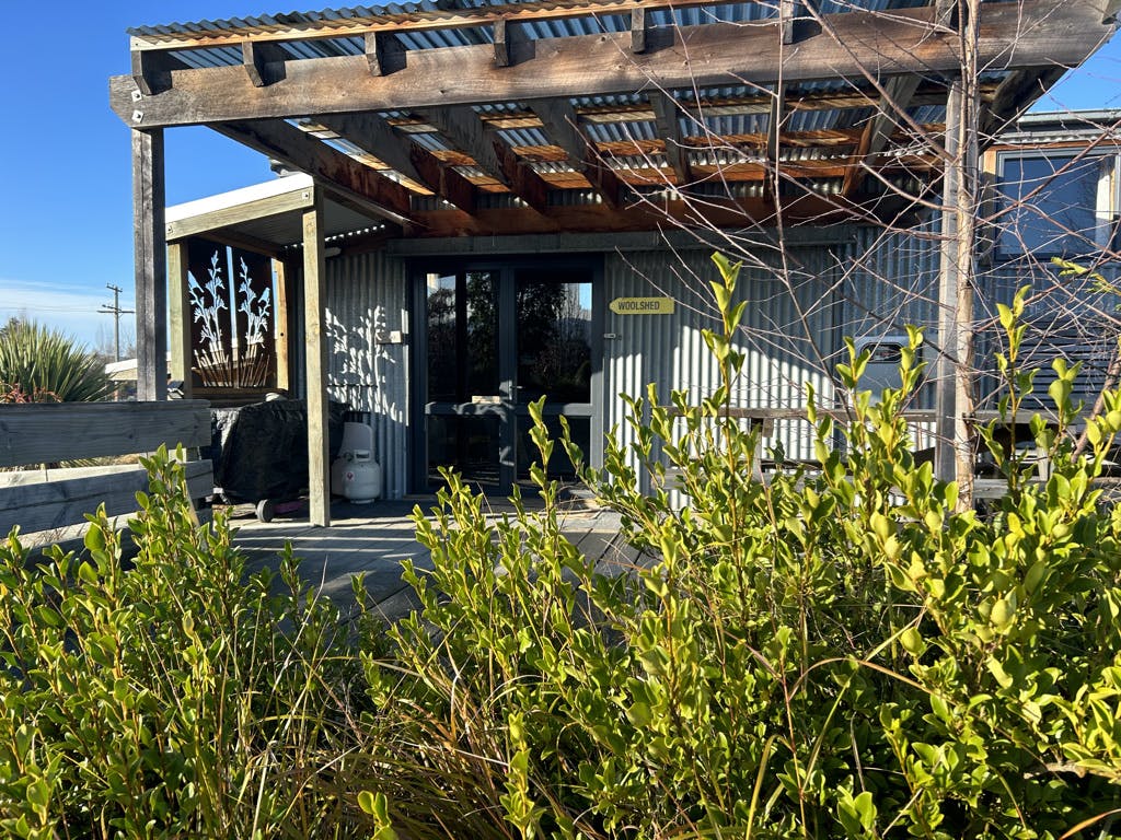 A covered porch beside a rustic cabin at Musterer's Accommodation, Fairlie.