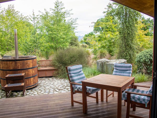 An outdoor eating area and hot tub with native plants at Musterer's Accommodation, Fairlie.