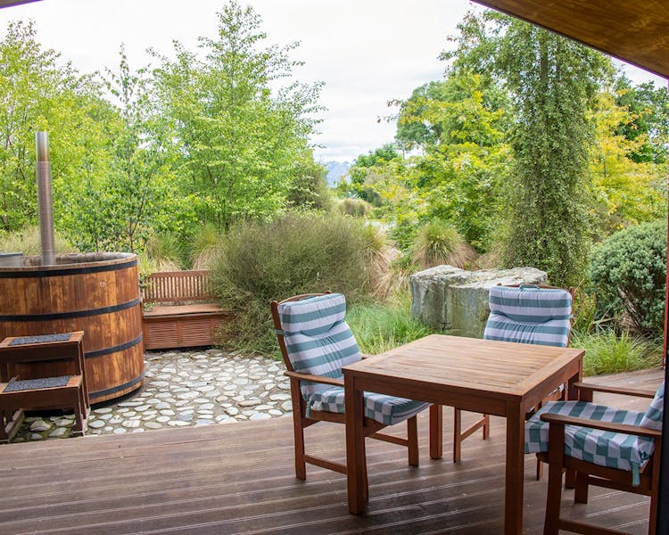 An outdoor eating area and hot tub with native plants at Musterer's Accommodation, Fairlie.