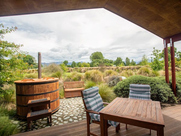 An outdoor eating area and hot tub with native plants at Musterer's Accommodation, Fairlie.