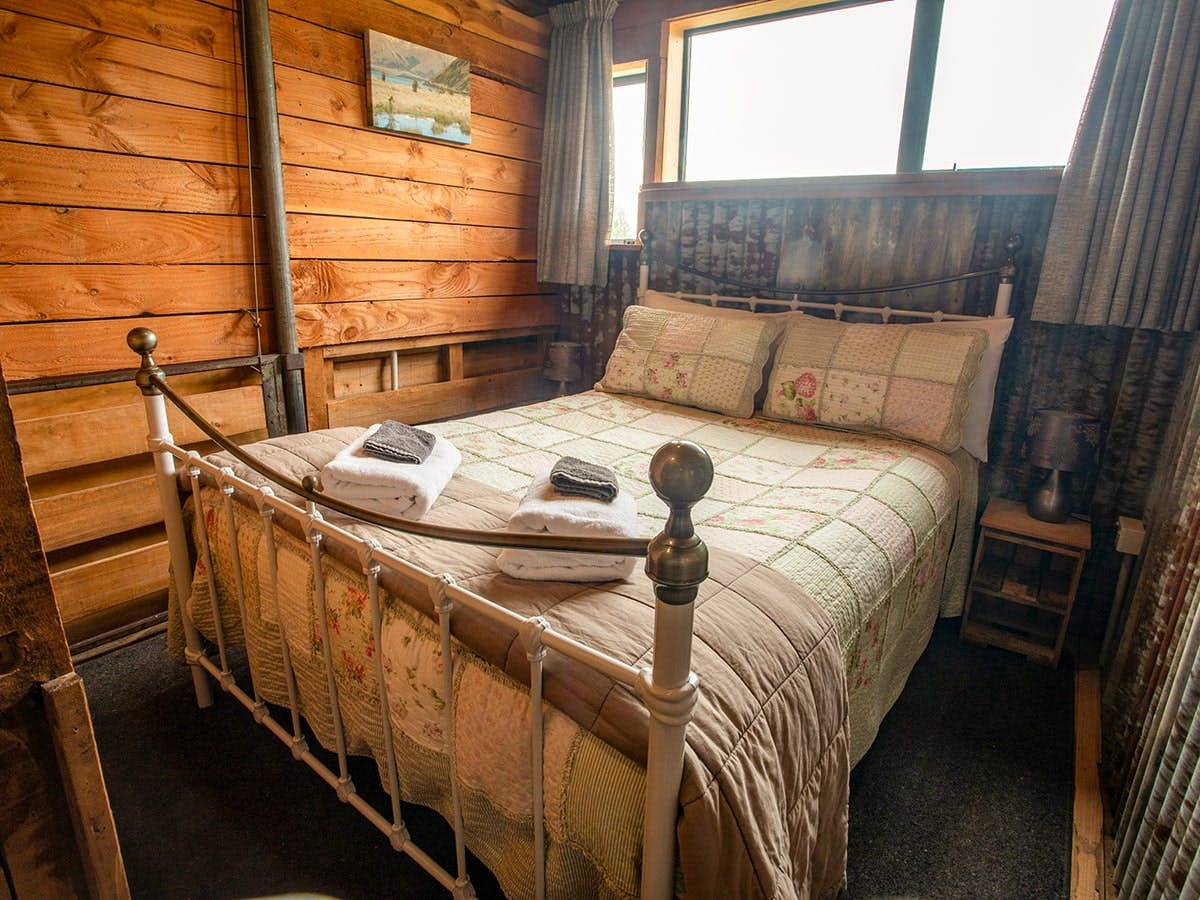 A timber room with large iron-framed bed at Musterer's Accommodation, Fairlie.