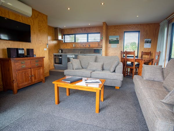 A modern-rustic living area with kitchen, couches, and wall tv at Musterer's Accommodation, Fairlie.