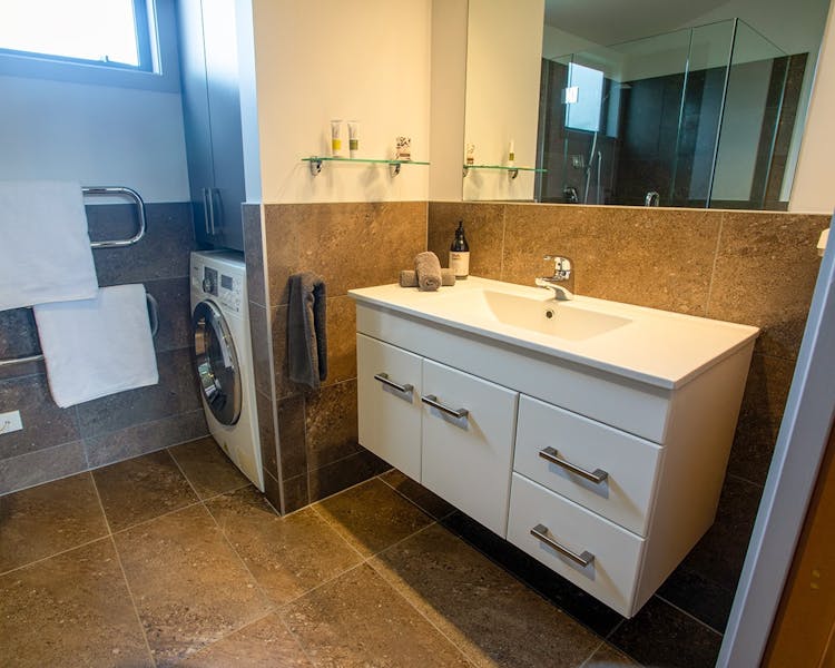 A rustic-modern bathroom with built-in laundry at Musterer's Accommodation, Fairlie.