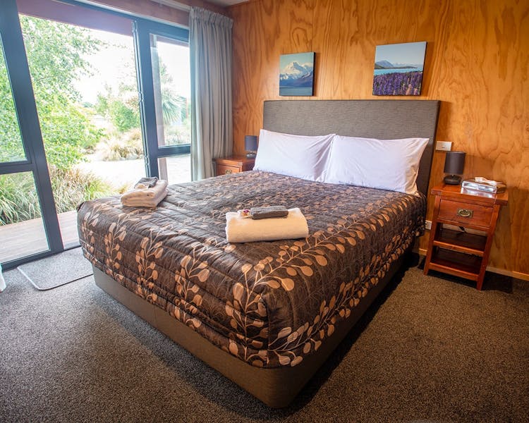 A timber bedroom with a large bed and glass doors at Musterer's Accommodation, Fairlie.
