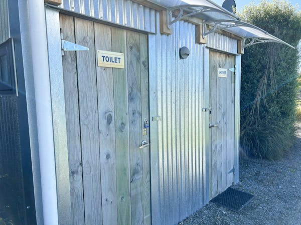 A wood and corrugated iron bathroom block with signage that says Toilet.