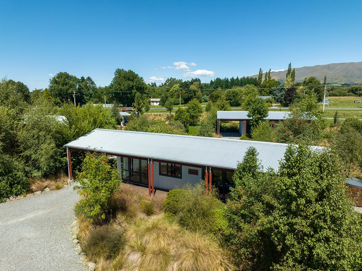 Rustic cabins with native trees and plants at Musterer's Accommodation, Fairlie.
