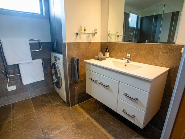 A tiled bathroom with built-in laundry at Musterer's Accommodation, Fairlie.