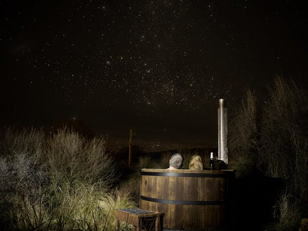 A couple in a hot tub stargazing at night at Musterer's Accommodation, Fairlie.