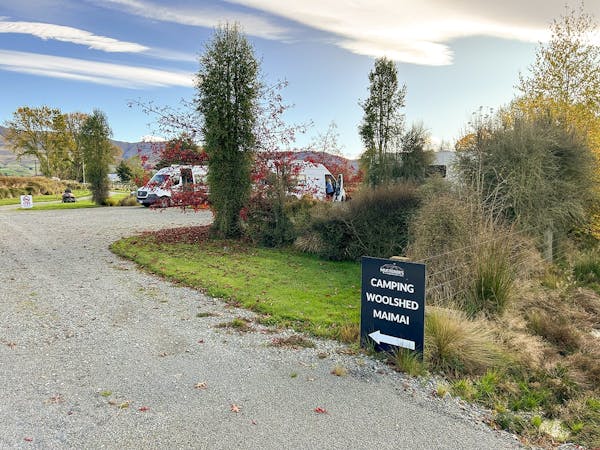 A driveway leading to a large campervan parking area with sign pointing to Camping, Woolshed, Maimai.