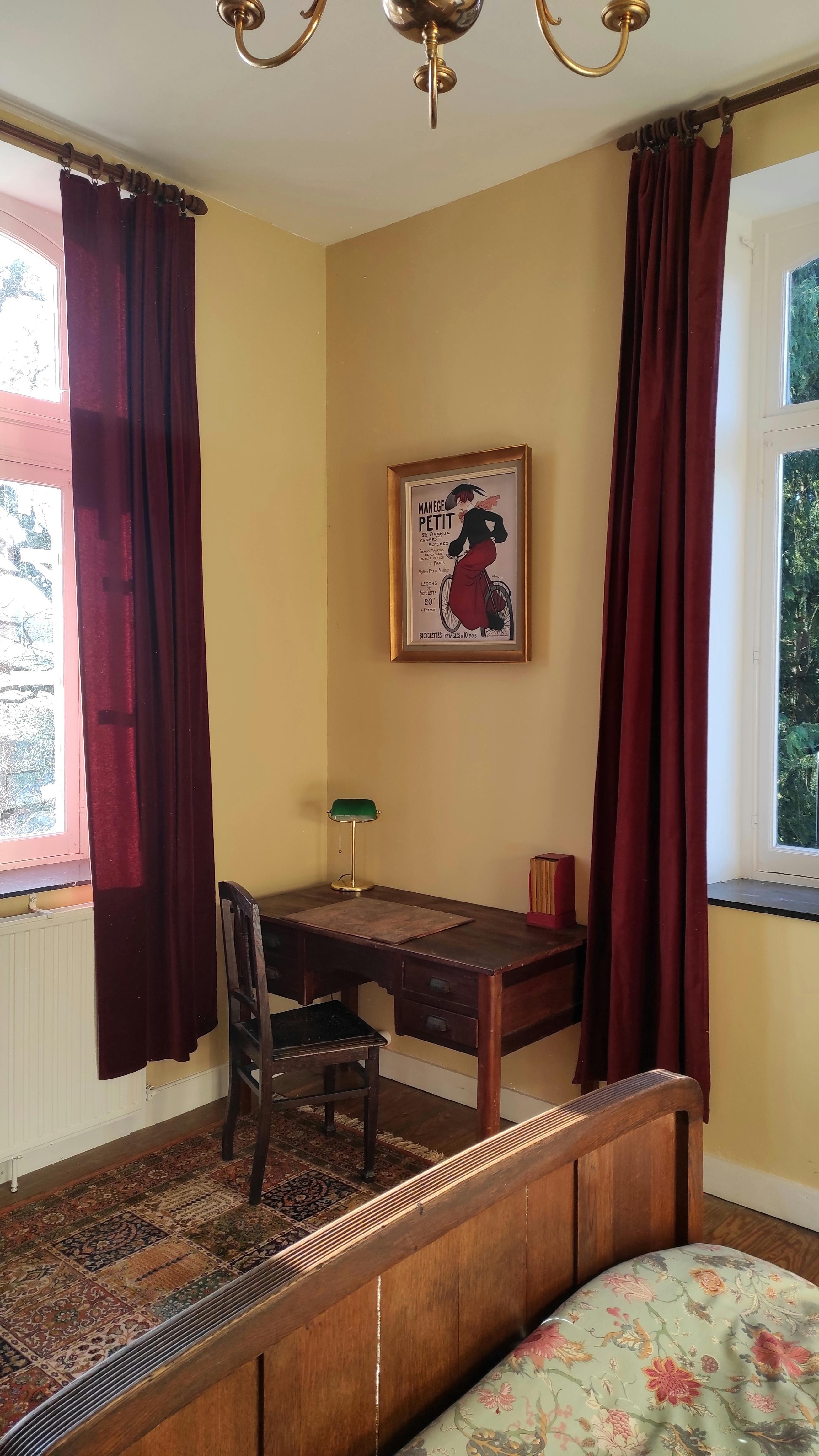 Charming spacious room at La Maison Vienvenue with a desk and authentic cycling-themed decoration.