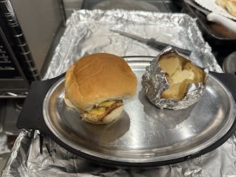 "Grilled cheese burger served with a loaded baked potato."