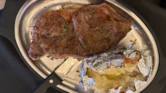 Cooked-to-order New York strip steak and a side of traditional baked potato at Best Bear Resort in Irons Michigan