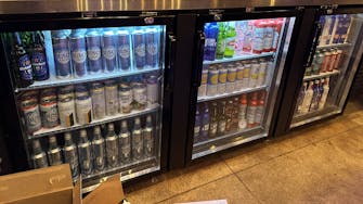 Bar stocked with various spirits, illuminated by a rhinestone 'Bar' sign.