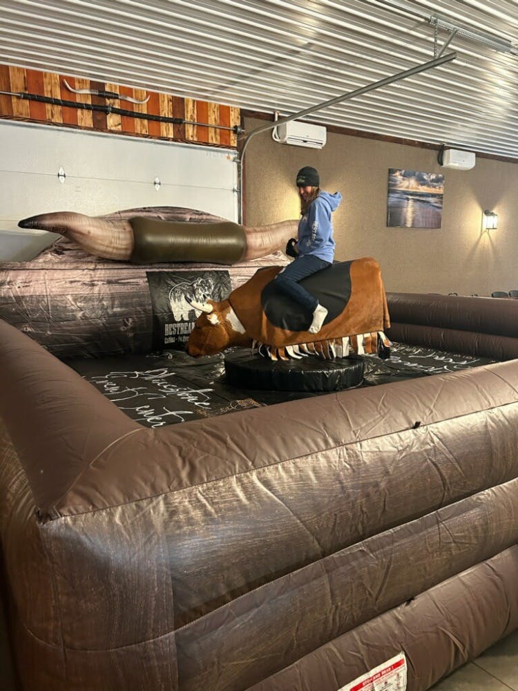 Carrie riding Billy the mechanical bull in the Rhinestone Event Center at Best Bear Lodge after renting an ORV.